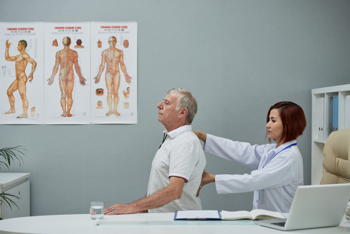 Chiropractor examining patient’s spine for posture and alignment before spine surgery in India