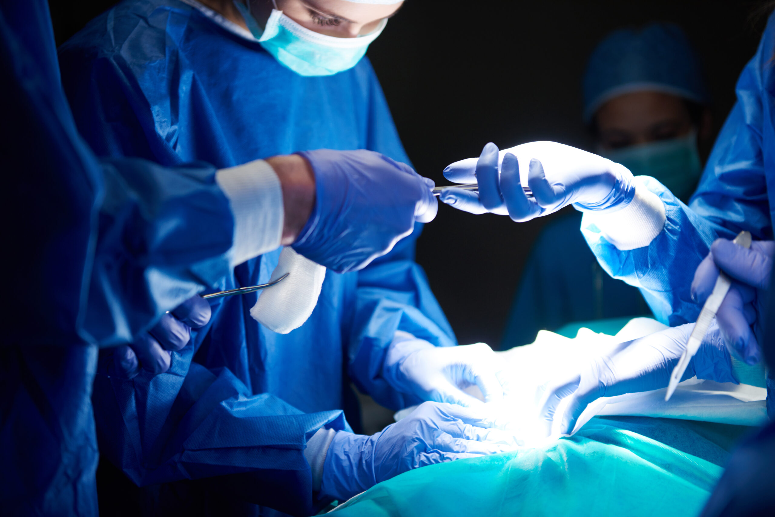 Team of gynecological surgeons passing surgical scissors in Indian operation theater – symbolizing precision and care in women's surgery