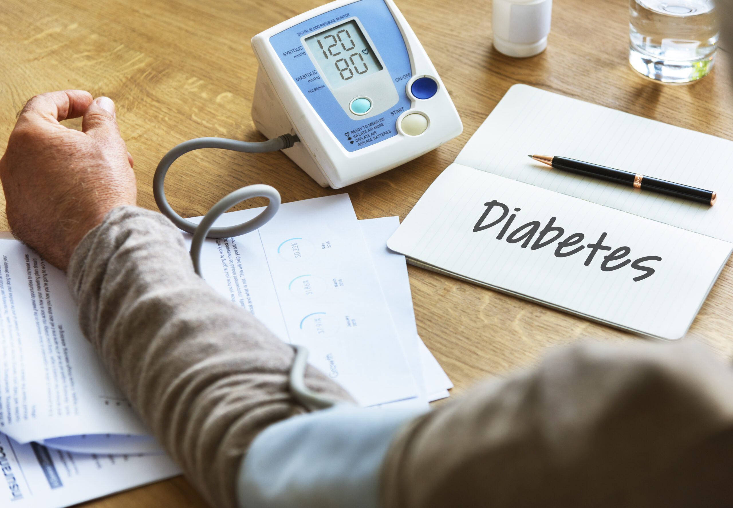 A person measuring blood pressure with a digital monitor beside a notebook labeled “Diabetes,” symbolizing health monitoring and treatment options such as metabolic surgery for diabetes in India