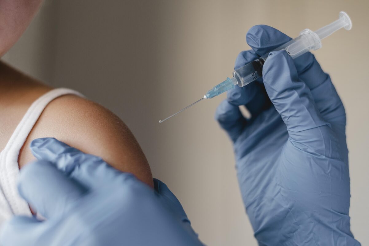 Close-up of a healthcare professional wearing blue gloves preparing to administer a vaccine injection into a patient’s arm, representing the HPV Vaccine in India.