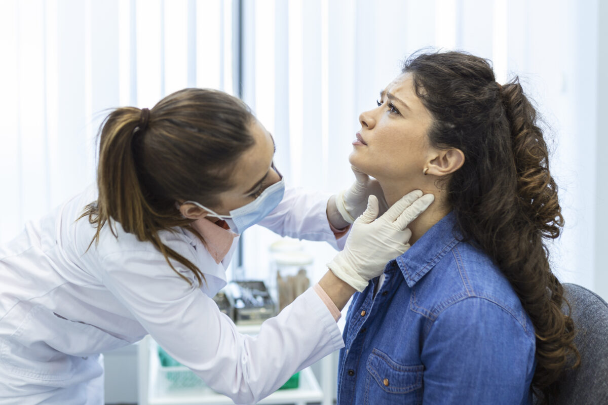 A doctor examining a woman’s neck for thyroid issues, representing diagnosis and treatment options like thyroid surgery in India.